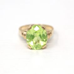 "Beautiful vintage circa 1940s era 10k yellow gold created green spinel ring! This lovely statement ring features an eye catching bright green 5.84 carat oval faceted created spinel, that is securely prong set. There are classic designs on the shoulders, and the shank is free of design. A wonderful 1940s era ring, featuring a pretty green stone!  ERA - Circa 1940s - Retro METAL / MATERIAL - 10k yellow gold, created spinel (approx. 5.84 CT) (Created spinel contains essentially the same chemical c Classic Oval Emerald Ring Collector's Item, Classic Oval Emerald Collectible Ring, Estate Style Oval Yellow Gold Rings, Vintage Oval Emerald Ring In 14k Gold, Yellow Gold Oval Estate Rings, Oval Yellow Gold Estate Rings, Vintage 14k Gold Emerald Ring With Center Stone, Vintage Green Emerald Ring With Center Stone, Antique Oval Rings For May Birthstone