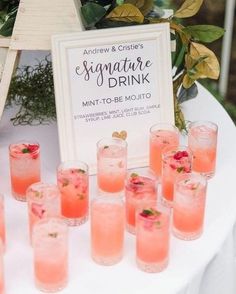 a table topped with lots of glasses filled with pink liquid next to a sign that says signature drink