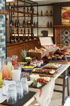 an assortment of food and drinks on a table in a restaurant with shelves full of bottles