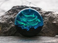 a blue and green pendant sitting on top of a rock