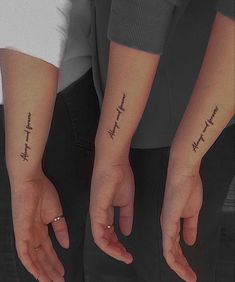 two people with matching tattoos on their arms holding hands and touching each other's fingers