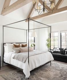 a bedroom with a four poster bed and chandelier hanging from it's ceiling