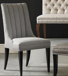 a pair of upholstered chairs in front of a black wall and white carpet