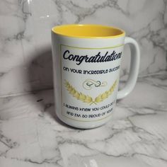 a coffee mug with congratulations on it sitting on a marble countertop next to a wall