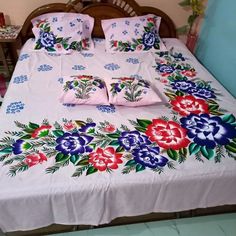 a bed covered in pink and blue flowers with matching pillows on it's headboard