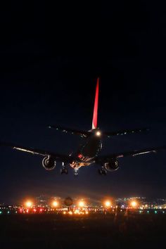 an airplane is taking off at night with lights on the ground and in the air