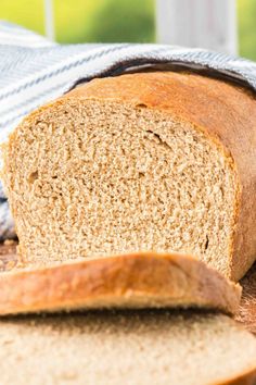 a loaf of whole wheat bread sitting on top of a wooden table next to a blue and white towel