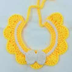 a yellow crocheted bib with a white bow on the front and side