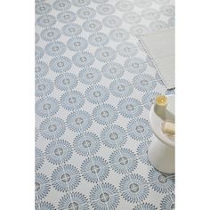 a blue and white tile floor with a vase on it