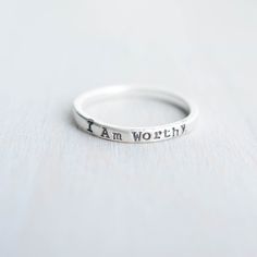 Skinny sterling silver ring that measures 2mm wide stamped with I am Worthy. Ring can come in sizes 4, 5, 6, 7, 8, 9, and 10. *Due to the process of hand stamping in each letter, the ring can stretch to be up to 1/2 size larger. Not sure of your ring size? Head over to this free printable to find your size. https://www.jewelry-secrets.com/Blog/wp-content/uploads/2015/05/Ring-Size-Chart1.pdf All Simpli Stamped jewelry comes ready to gift, packaged in a charming kraft box, tied with a coordinating Meaningful Everyday Sterling Silver Stackable Rings, Meaningful Stackable Sterling Silver Rings For Everyday, Meaningful Silver Stackable Rings, Meaningful Sterling Silver Stackable Rings For Everyday, Spiritual Sterling Silver Stackable Rings For Promise, Everyday Sterling Silver Stackable Rings, Meaningful Stackable Engraved Sterling Silver Ring, Meaningful Engraved Sterling Silver Stackable Ring, Meaningful Sterling Silver Stackable Engraved Ring