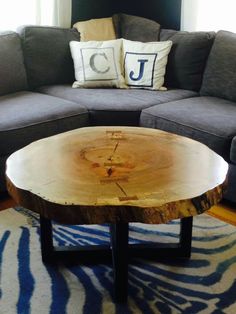 a large wooden table sitting in front of a gray couch on top of a blue and white rug