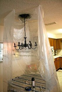 a room with a bed and chandelier hanging from it's ceiling in front of a kitchen