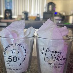 two glasses sitting on top of a counter with tissue paper in each glass and the words happy birthday written on them