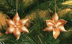 two gold ornaments hanging from a christmas tree