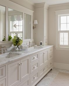 a large bathroom with two sinks and mirrors on the wall, along with white cabinetry