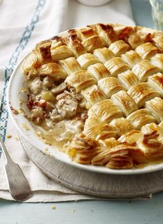 a chicken and bacon lattice pie on a plate with a glass of water next to it