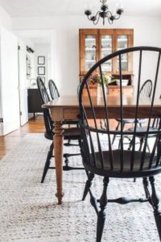 a dining room table with black chairs and a rug on the floor in front of it