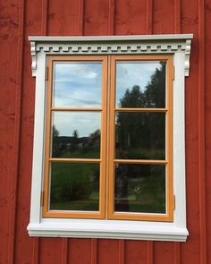 a red building with two windows and a white trim around the window sill is shown