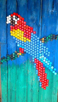 a colorful parrot painted on the side of a wooden door with lots of bottle caps