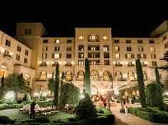 the building is lit up at night and people are walking around in the courtyard area