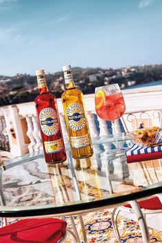 three bottles of alcohol sitting on top of a glass table