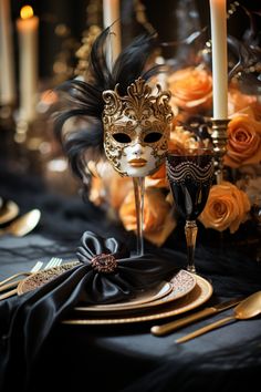 a table topped with black cloth covered plates and goldware next to a tall candle