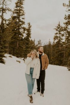 a man and woman are standing in the snow