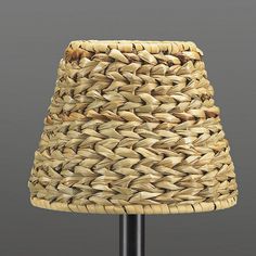 a lamp made out of woven material on a black metal base with a light shade