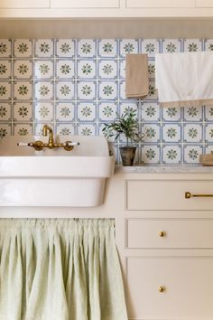 a white sink sitting under a window next to a counter top with towels hanging on it