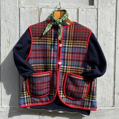 a plaid jacket hanging on a wooden door with a green and red scarf around it