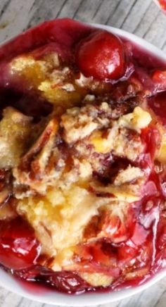 a close up of a bowl of food with cherries on the top and bread in the middle