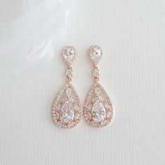 two pairs of diamond earrings on a white surface