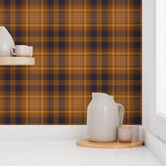 an orange and black plaid wallpaper with white vases on the shelf next to it