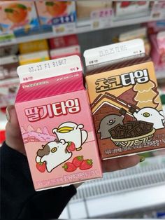 two boxes of food are held up in a store's display case, one is pink and the other is brown