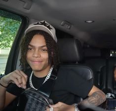 a young man sitting in the back seat of a car holding onto his handbag