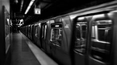 black and white photograph of a subway train at a station with its doors open in the dark