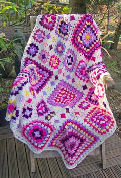 a crocheted blanket sitting on top of a wooden bench