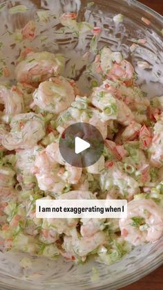 a glass bowl filled with shrimp salad on top of a wooden table