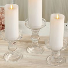 three candles are sitting in glass dishes on a table