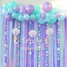 there are balloons and streamers on the wall with mermaids in them for a birthday party