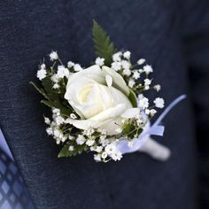 a boutonniere with white flowers on the lapel of a man in a suit