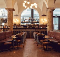 the interior of a restaurant with leather booths and bar stools in front of large arched windows