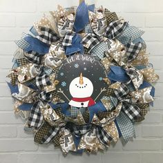 a christmas wreath with a snowman on the front and blue ribbon around it that says let it snow