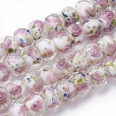 three strands of glass beads with pink flowers on white and gold foiled background