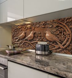 a kitchen counter with a pot on top of it and two birds carved into the wall