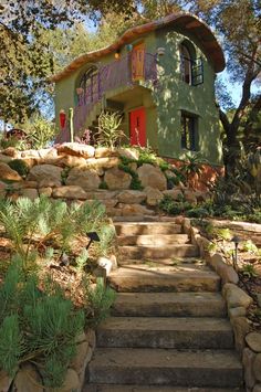 stairs lead up to the front door of a green house with colorful decorations on it