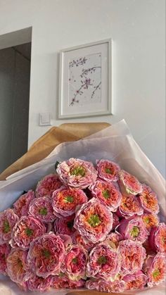 a bouquet of pink flowers sitting on top of a wooden table next to a mirror