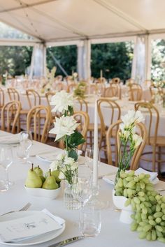 the tables are set with white flowers and green grapes in vases on each table