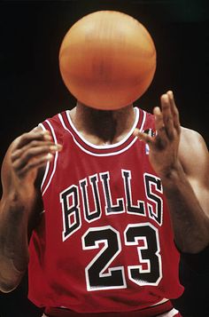 a basketball player is about to dunk the ball into his face with one hand