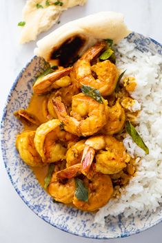 a blue and white plate topped with rice and shrimp